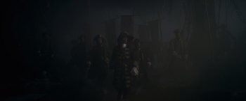 Movie still from “Pirates of the Caribbean: On Stranger Tides” (2011), directed by Rob Marshall – A group of men in period clothing standing in a dark room; Wide shot, Low angle