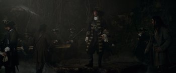 Movie still from “Pirates of the Caribbean: On Stranger Tides” (2011), directed by Rob Marshall – A man dressed as a pirate standing on a tree stump; Wide shot, Low angle