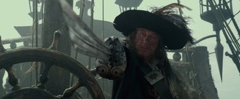 Movie still from “Pirates of the Caribbean: On Stranger Tides” (2011), directed by Rob Marshall – A man wearing a pirate hat standing next to a steering wheel; Close Up shot, Low angle