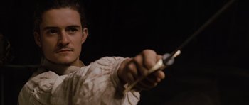 Movie still from “Pirates of the Caribbean: The Curse of the Black Pearl” (2003), directed by Gore Verbinski – A young man holding a sword in his hand; Close Up shot, Over the shoulder angle