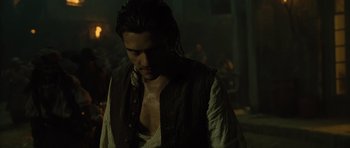 Movie still from “Pirates of the Caribbean: The Curse of the Black Pearl” (2003), directed by Gore Verbinski – A man in a pirate costume looking down at his chest; Medium shot, Over the shoulder angle