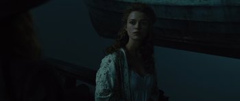 Movie still from “Pirates of the Caribbean: The Curse of the Black Pearl” (2003), directed by Gore Verbinski – A woman in a white dress standing next to a boat; Medium shot, Low angle