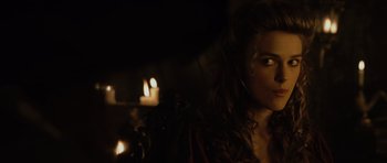 Movie still from “Pirates of the Caribbean: The Curse of the Black Pearl” (2003), directed by Gore Verbinski – A woman with curly hair standing in front of a fireplace; Close Up shot, Over the shoulder angle