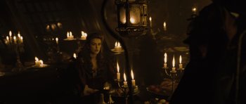 Movie still from “Pirates of the Caribbean: The Curse of the Black Pearl” (2003), directed by Gore Verbinski – A woman sitting in front of a group of lit candles; Medium shot, Over the shoulder angle