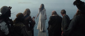 Movie still from “Pirates of the Caribbean: The Curse of the Black Pearl” (2003), directed by Gore Verbinski – A woman in a white dress standing in front of a body of water; Wide shot, Over the shoulder angle