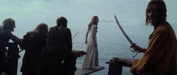 Movie still from “Pirates of the Caribbean: The Curse of the Black Pearl” (2003), directed by Gore Verbinski – A woman in a white dress standing on a pier; Wide shot, Over the shoulder angle