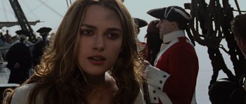 Movie still from “Pirates of the Caribbean: The Curse of the Black Pearl” (2003), directed by Gore Verbinski – A woman's face in front of a group of people; Close Up shot, Over the shoulder angle