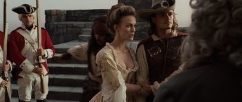Movie still from “Pirates of the Caribbean: The Curse of the Black Pearl” (2003), directed by Gore Verbinski – A beautiful young woman in a dress next to a man in a cowboy hat; Medium shot, Over the shoulder angle