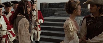 Movie still from “Pirates of the Caribbean: The Curse of the Black Pearl” (2003), directed by Gore Verbinski – A man in a red and white uniform holding a rifle; Medium shot, Over the shoulder angle