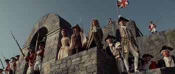 Movie still from “Pirates of the Caribbean: The Curse of the Black Pearl” (2003), directed by Gore Verbinski – A group of people standing on top of a stone wall; Wide shot, Low angle