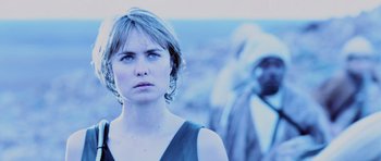 Movie still from “Pitch Black” (2000), directed by David Twohy – A woman standing in front of an indian; Close Up shot, Over the shoulder angle