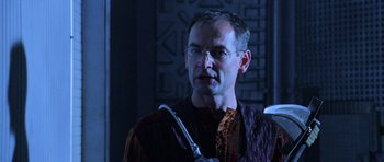 Movie still from “Pitch Black” (2000), directed by David Twohy – A man with glasses is holding something in his hand; Close Up shot, Over the shoulder angle