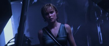 Movie still from “Pitch Black” (2000), directed by David Twohy – A woman in a black top is standing in the dark; Close Up shot, Low angle