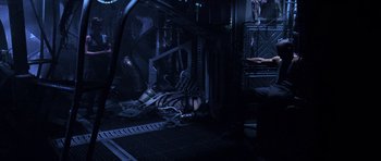 Movie still from “Pitch Black” (2000), directed by David Twohy – A man laying on the ground in a dark room; Wide shot, High angle