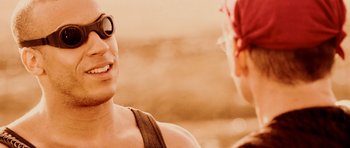 Movie still from “Pitch Black” (2000), directed by David Twohy – A man wearing sunglasses talking to another man; Close Up shot, Over the shoulder angle