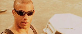 Movie still from “Pitch Black” (2000), directed by David Twohy – A man wearing sunglasses and a tank top; Close Up shot, High angle