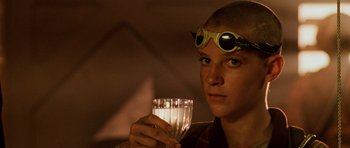 Movie still from “Pitch Black” (2000), directed by David Twohy – A person with goggles holding a glass of water; Close Up shot, Over the shoulder angle