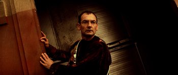 Movie still from “Pitch Black” (2000), directed by David Twohy – A man in a brown shirt and a brown jacket; Close Up shot, Low angle