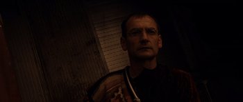 Movie still from “Pitch Black” (2000), directed by David Twohy – A man with glasses is standing in a dark room; Close Up shot, Low angle