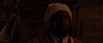 Movie still from “Pitch Black” (2000), directed by David Twohy – A man with a turban on his head looking into the distance; Close Up shot, Low angle