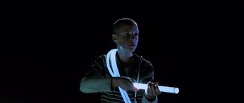 Movie still from “Pitch Black” (2000), directed by David Twohy – A young man holding a white object in his hands; Medium shot, Low angle