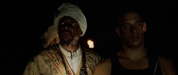 Movie still from “Pitch Black” (2000), directed by David Twohy – A man in a turban and a man in a black shirt; Close Up shot, Low angle