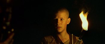 Movie still from “Pitch Black” (2000), directed by David Twohy – A boy with a shaved head is looking at the camera; Close Up shot, Low angle