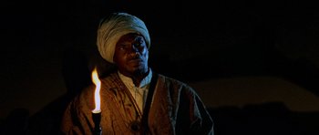 Movie still from “Pitch Black” (2000), directed by David Twohy – A man with a turban on holding a lit candle; Close Up shot, Low angle