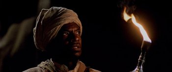 Movie still from “Pitch Black” (2000), directed by David Twohy – A man with a turban is looking into the distance; Close Up shot, Over the shoulder angle