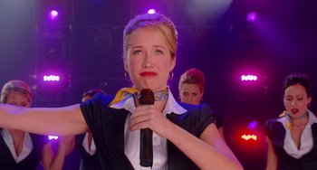 Movie still from “Pitch Perfect” (2012), directed by Jason Moore – A woman holding a microphone up to her mouth; Medium shot, Low angle
