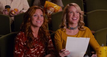 Movie still from “Pitch Perfect” (2012), directed by Jason Moore – Two women are sitting in a theater holding papers; Medium shot, Low angle