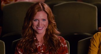 Movie still from “Pitch Perfect” (2012), directed by Jason Moore – A woman with long red hair smiling for the camera; Close Up shot, High angle