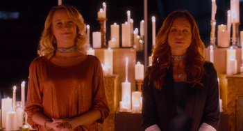 Movie still from “Pitch Perfect” (2012), directed by Jason Moore – Two women standing next to each other in front of candles; Medium shot, Low angle