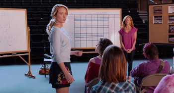 Movie still from “Pitch Perfect” (2012), directed by Jason Moore – A group of people sitting in front of a whiteboard; Medium shot, Over the shoulder angle
