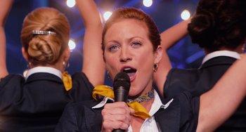 Movie still from “Pitch Perfect” (2012), directed by Jason Moore – A woman is singing into a microphone; Medium shot, Low angle