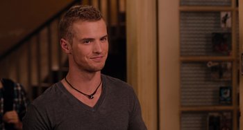 Movie still from “Pitch Perfect” (2012), directed by Jason Moore – A young man wearing a necklace and looking to his left; Close Up shot, Over the shoulder angle