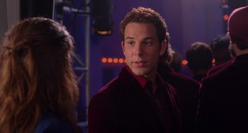 Movie still from “Pitch Perfect” (2012), directed by Jason Moore – A young man in a red velvet jacket is looking at the camera; Close Up shot, Over the shoulder angle
