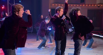 Movie still from “Pitch Perfect” (2012), directed by Jason Moore – A group of men in velvet jackets singing and dancing on a stage; Wide shot, High angle
