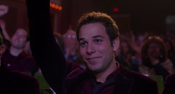 Movie still from “Pitch Perfect” (2012), directed by Jason Moore – A young man is smiling and raising his hand; Close Up shot, Over the shoulder angle