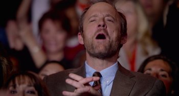 Movie still from “Pitch Perfect” (2012), directed by Jason Moore – A man in a brown suit and a brown neck tie; Close Up shot, Low angle