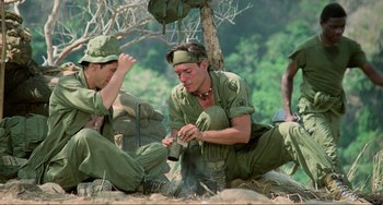 Movie still from “Platoon” (1986), directed by Oliver Stone – A group of men sitting next to each other on the ground; Medium shot, High angle