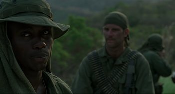 Movie still from “Platoon” (1986), directed by Oliver Stone – Two men in military fatigues are standing in the woods; Close Up shot, Over the shoulder angle