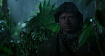 Movie still from “Platoon” (1986), directed by Oliver Stone – A man wearing a rain jacket and a rain hat; Medium shot, Low angle