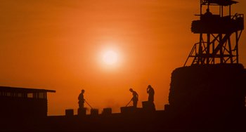 Movie still from “Platoon” (1986), directed by Oliver Stone – Three men working on a construction site at sunset; Extreme Wide shot, Low angle