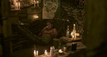 Movie still from “Platoon” (1986), directed by Oliver Stone – A man sitting in a hammock eating a sandwich; Wide shot, High angle