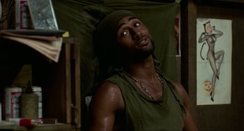 Movie still from “Platoon” (1986), directed by Oliver Stone – A man with a bandana on his head is sitting in a chair; Close Up shot, High angle