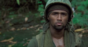Movie still from “Platoon” (1986), directed by Oliver Stone – A man with a beard wearing a hat and a scarf; Close Up shot, High angle