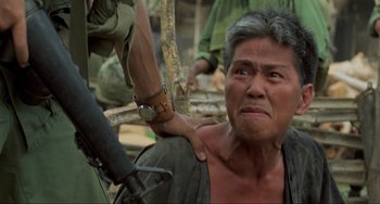 Movie still from “Platoon” (1986), directed by Oliver Stone – An old man being held down by a man with a gun; Close Up shot, Over the shoulder angle