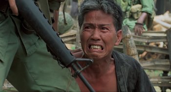 Movie still from “Platoon” (1986), directed by Oliver Stone – A man with a gun in his hand and his mouth open; Close Up shot, Over the shoulder angle
