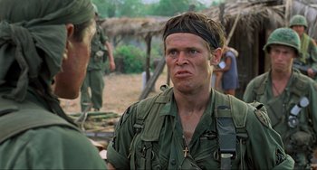 Movie still from “Platoon” (1986), directed by Oliver Stone – A man in a military uniform is talking to another man; Close Up shot, Over the shoulder angle